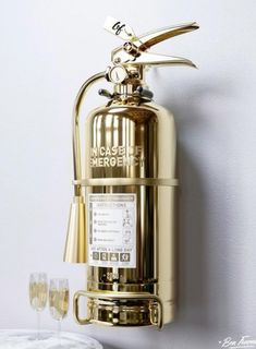 a brass colored fire extinguisher with two glasses on the table next to it