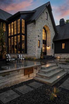 a large house with stone steps leading up to the front door and patio area at dusk