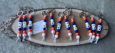 six keychains with different colored beads and skulls on them are sitting on a piece of wood