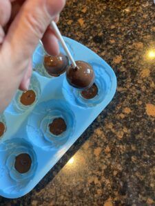 a person is dipping some chocolates into ice cubes with a toothpick