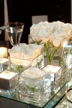 two vases filled with flowers on top of a table next to wine glasses and silverware