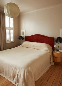 a bedroom with a bed and two lamps on either side of the bed, in front of a window