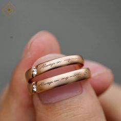 two gold wedding bands with the words always on my finger written in cursive writing