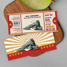 two ticket cards with an image of a train on the front and back, sitting on top of a cutting board