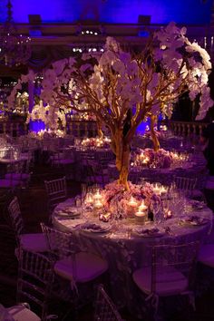 the centerpieces are decorated with flowers, candles and branches in varying shades of purple