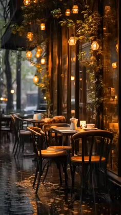 an empty restaurant with tables and chairs in the rain, lit by lanterns hanging from the ceiling