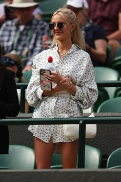 a woman standing in the stands holding a bottle