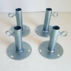 three metal candlesticks sitting on top of a white table next to each other