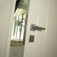 an open door with a handle on the front and side doors to another building in the background