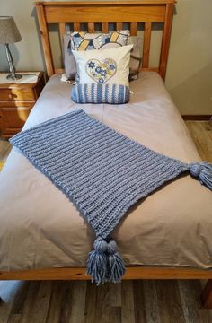 a crocheted blanket on top of a bed next to pillows and a lamp