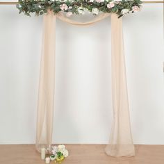 a wedding arch with flowers and greenery on the table next to candlelight candles