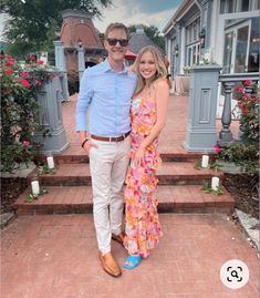 a man and woman posing for a photo in front of some flowers on the steps