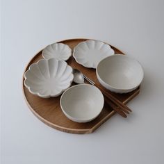 a wooden tray topped with white bowls and chopsticks