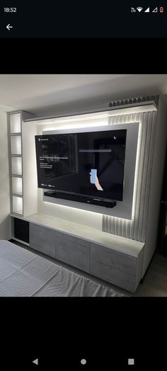 a large flat screen tv mounted to the side of a wall next to a bed