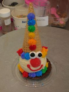 an ice cream cone with a clown face on it's head and pom poms around the top