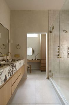 a bathroom with marble counter tops and white tile flooring, along with a walk in shower