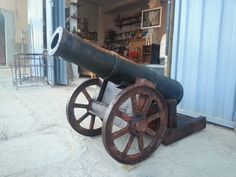 an old cannon is sitting in the middle of a room with blue walls and windows