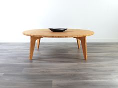 a wooden table with a black bowl on it's top sitting on the floor