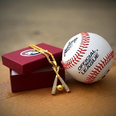 a baseball with a gold chain on it sitting next to a box and a necklace