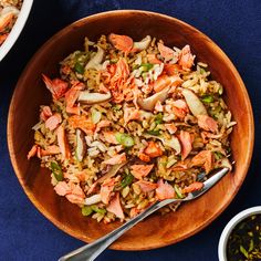 a bowl filled with rice and meat next to two bowls of vegetables on a blue table cloth