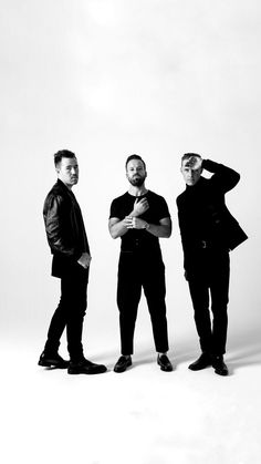 three men standing next to each other in front of a white background with one holding his head