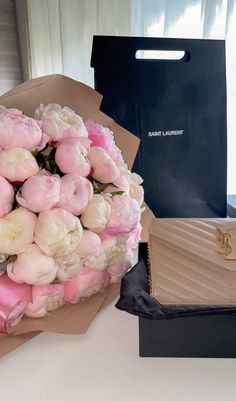 a bouquet of pink and white flowers sitting on top of a table next to a purse