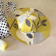 a polka dot hat sitting on top of a yellow plate next to a bottle of lotion