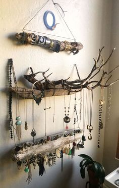 a wall hanging made out of branches and other items on it's side, with various necklaces attached to the hooks