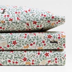 three pillows are stacked on top of each other in front of a white background with red and green flowers