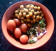 an orange bowl filled with different types of food on top of a black countertop