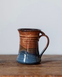 a brown and blue mug sitting on top of a wooden table