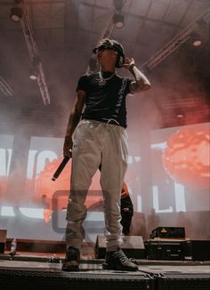 a man standing on top of a stage with a microphone in his hand and headphones to his ear