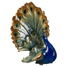 a glass peacock figurine sitting on top of a white table next to a blue vase