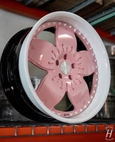 a pink and white wheel on top of a red car with riveted rims