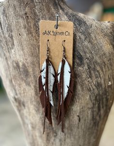 two brown and white feather earrings hanging from a tree