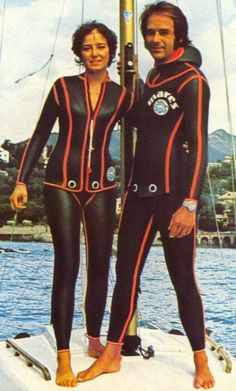 two people in wet suits standing on a boat