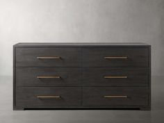 a black dresser with gold handles and drawers on the bottom, in front of a gray wall