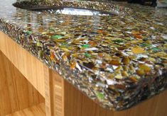 the counter top is made out of many different colored glass shards and wood planks