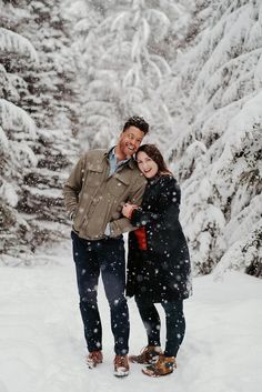 a man and woman standing in the snow with trees covered in snow behind their backs