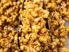 a spoon filled with caramel popcorn on top of a table