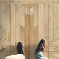 a person standing on top of a wooden floor next to a pair of brown shoes