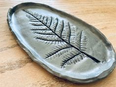 a metal leaf shaped dish sitting on top of a wooden table