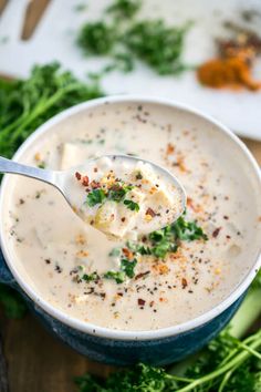 a spoon full of soup sitting on top of a wooden table next to broccoli