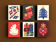 four christmas cards are arranged on a brown surface, each with an ornament