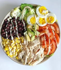 a salad with eggs, tomatoes, black beans, corn, lettuce and dressing