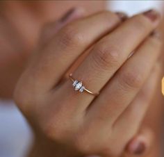 a woman's hand with a diamond ring on top of her finger and two diamonds in the middle