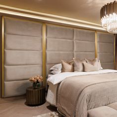 a large bed sitting in a bedroom next to a chandelier above it's headboard