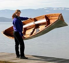 a woman standing on a dock holding a wooden boat