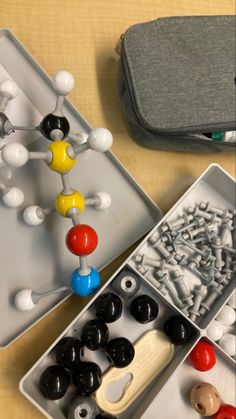 an assortment of bead and button making materials in trays on a wooden table