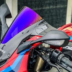 a red and blue motorcycle parked next to a building